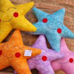 Cojines infantiles con forma de estrella en alegres y brillantes colores. El cojín estrella es el cojín ideal para decorar dormitorios de bebés y niños.